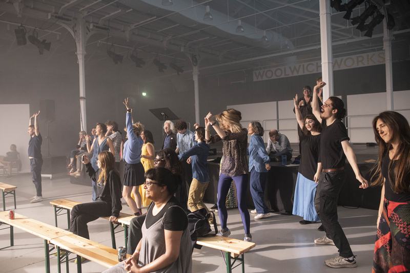 A group of people dancing wildly and laughing in a performance space.